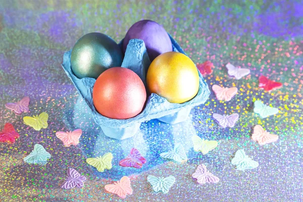 Easter. Painted eggs of yellow, pink, purple, green, turquoise pearl color in blue packaging on a holographic rainbow background with a copy space — Stock Photo, Image