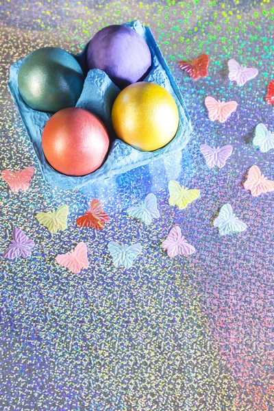 Wielkanoc. Pisanki, żółty, różowy, fioletowy, zielony, turkusowy kolor perłowy w niebieskie opakowania na holograficznych tęcza tło z miejsca kopii — Zdjęcie stockowe