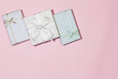 Pembe, gümüş, soluk mavi, bir kopya alanı ile hassas pembe arka plan üzerinde pastel renklerde bir yay ile renk kutuları bir ürün yelpazesine ile hediye sarma ile Festival arka plan