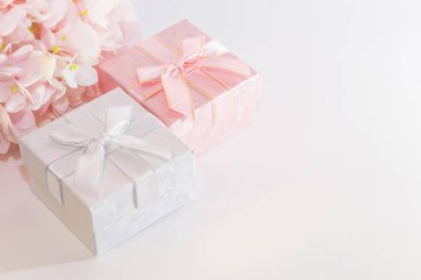 Kopya alanı ile beyaz bir arka plan üzerinde pastel renklerde yapay ortanca ve yapay ortanca çiçekleri ile pembe ve gümüş hediye kutusu ile bir tebrik kartı için Şenlikli arka plan