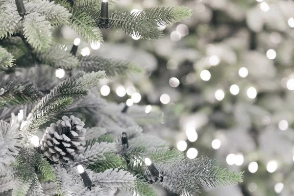 Capodanno e arredamento natalizio. Sfondo festivo con uno spazio di copia con una struttura di rami artificiali decorativi ricoperti di neve lucenti di alberi di Natale di colore verde con coni — Foto Stock