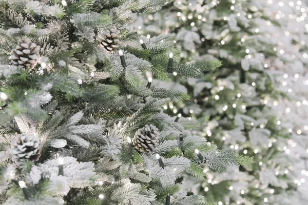 New Year and Christmas decor. Festive background with a copy space with a texture of decorative artificial shining snow-covered branches of Christmas trees of green color with cones — Stock Photo, Image