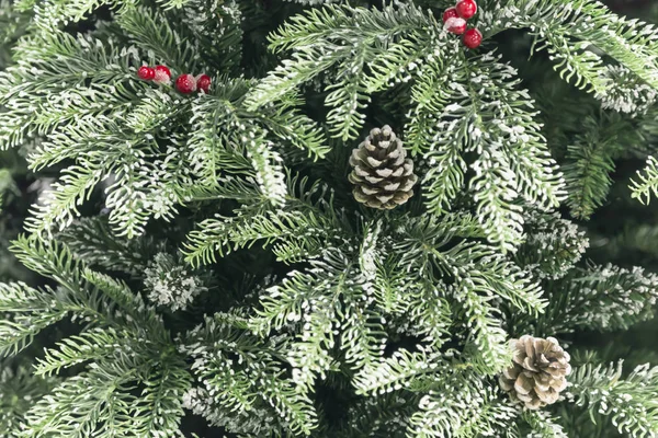 Decoración de Año Nuevo y Navidad. Fondo festivo con textura de decorativos artificiales brillantes ramas cubiertas de nieve de árboles de Navidad de color verde con conos —  Fotos de Stock
