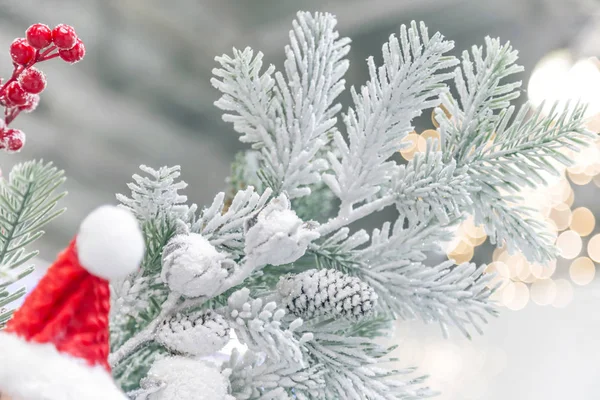 Capodanno e arredamento natalizio. Fondo festivo con rami artificiali decorativi ricoperti di neve dell'albero di Natale in verde con pigne e cappello di Babbo Natale — Foto Stock