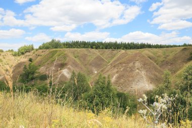 Toprak erozyonu. Doğa açık havada sıcak bir yaz gününde bulutlar ile parlak mavi gökyüzünün arka planda pitoresk sıradışı bir vadi ve bir barrow ile Manzara