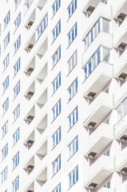 Mimaride İnşaat ve geometri yapı. Balkon ve pencerelerin bulunduğu yeni yüksek katlı parlak evin cephesi ile endüstriyel arka plan