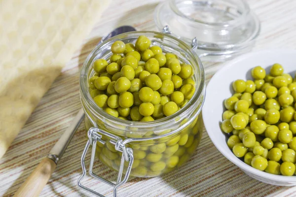 Inicio Conservas de cultivo de frijoles de verano, dieta vegetariana vegetal comida saludable, guisantes verdes naturales marinado en un frasco de vidrio y un plato blanco sobre un fondo de mesa —  Fotos de Stock