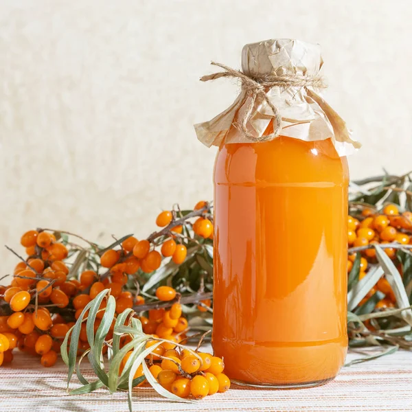 Vegetarian food, healthy nutrition, preserving the harvest of ripe juicy sea-buckthorn, preparing fresh healthy vitamin drink and healing broth. Jug with juice and branches of orange sea buckthorn