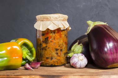 Ev yapımı konserve, haşlanmış sebze konservesi patlıcan, biber ve sarımsakla pişirilmiş havyar ahşap bir arka planda, cam bir kavanozda kırsal tarzda. Ev hizmeti