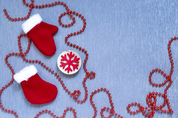 Anno nuovo, sfondo di Natale posa piatta. Giocattoli di festa cuciti, calzino, guanti, fiocco di neve di legno e ghirlanda rossa decorativa su una superficie blu con una struttura di tessuto di copia-spazio — Foto Stock