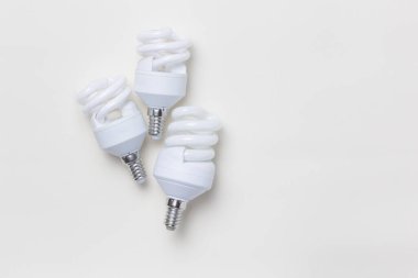 Elektrik konsepti, ışıklandırma, elektrikli aletler, ev eşyaları. Üç modern elektrik enerjisi, beyaz spiral ampulleri açık katı renk arkaplanında fotokopi alanı ile kaydediyor.