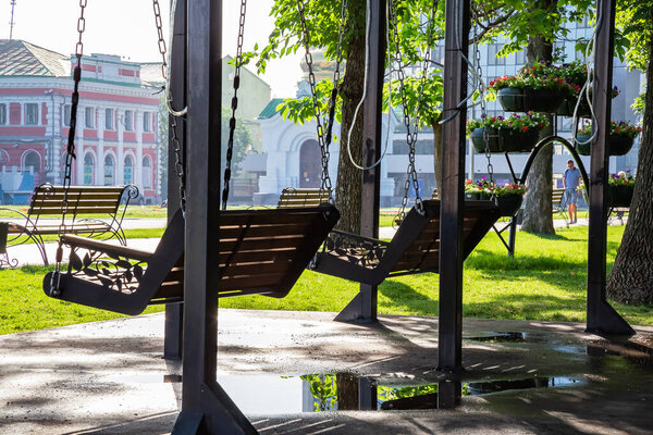 Saratov, Russia - 07/06/2020: Empty swing in the park in summer in the park named after Radishchev overlooking Teatralnaya Square, a recreation area in the city among green trees