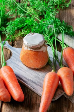 Kavanozda sarımsak ve yabanturpu ile konserve havuç salatası, taze sebzeler, ev yapımı diyet vitamin reçelleri, doğal ahşap masa arkasında çorba için rendelenmiş havyar sosu.