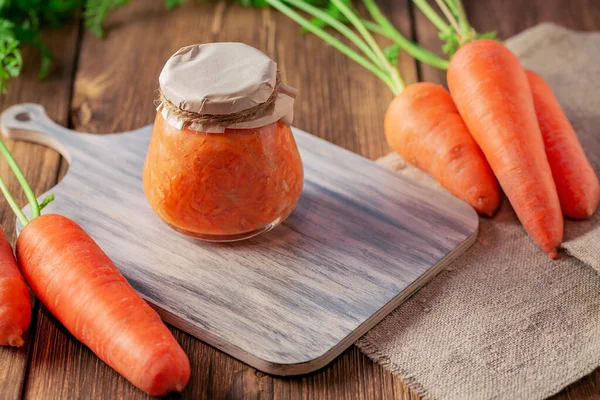 Canned carrot sauce salad with garlic and horseradish in a jar with fresh vegetables, recipe homemade diet vitamin preserves, chopped grated caviar dressing for soup on natural wooden table background — Stock Image Canned Carrot Sauce Salad Garlic Horseradish Jar Fresh Vegetables Recipe Stock Photo