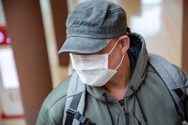 Coronavirüs salgını sırasında halka açık bir yerde 40-45 yaşlarında beyaz bir maske takan Avrupalı bir adam Covid-19 salgınından korunuyor.
