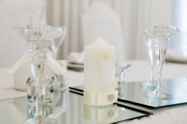 Tablo yeni evliler akşam yemeği için lüks restoranda, görünümü kapatın. Beyaz mum, çatal bıçak takımı ayna üzerinde.