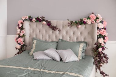 Şık yatak odası iç tasarım çiçekler ile beyaz ve gri yastık yatak. Lüks yatak ev iç tasarım gerçek fotoğraf.