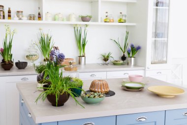 Tablo, yeşil çiçek, pasta, tabaklar, beyaz mobilya modern parlak mutfak. Mutfak iç, bahar zaman kavramı.