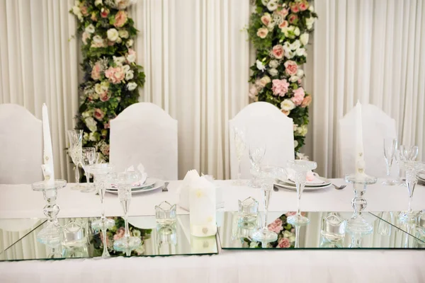 テーブルは高級レストランで新婚夫婦の夕食に提供しています 白いキャンドル ミラー カトラリーの花装飾 — ストック写真