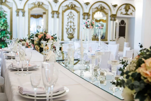 テーブルは高級レストランで新婚夫婦の夕食に提供しています 白のキャンドル ミラー 装飾花のカトラリー 装飾が施されたホールは — ストック写真