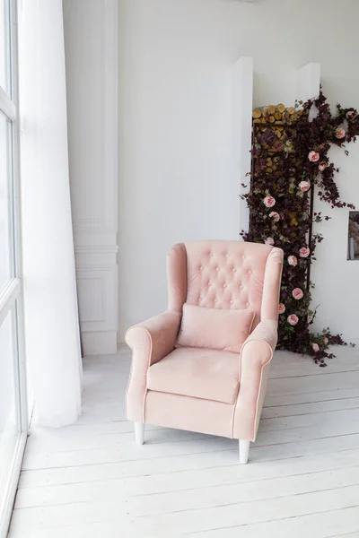 Pink armchair in living room, home interior. Photo of living room in light colors, home interior design.