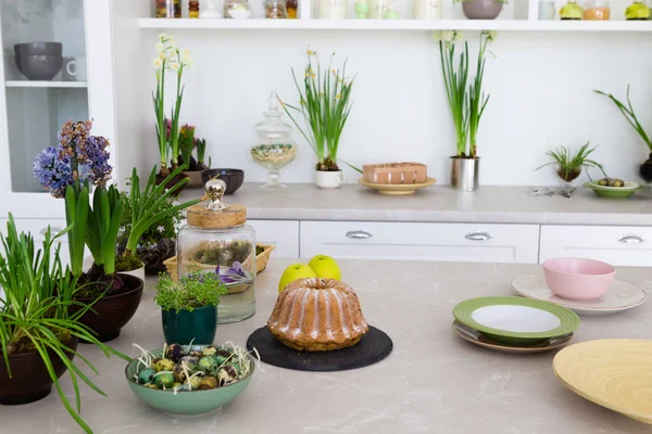 Сучасна Світла Кухня Столом Зеленими Квітами Тортами Тарілками Білими Меблями — стокове фото