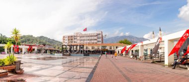 Kemer, Turkey - Ekim, 2018: Kemer, Türkiye'de merkezi kare panoramik. Türkiye, modern binalar ve arka plan üzerinde Dağları bayrağı.