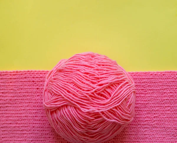 Piece of pink knitting, yellow background. — Stock Photo, Image