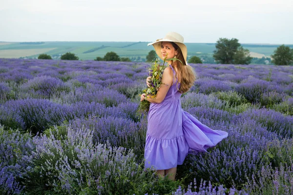 Kvinna i lila klänning och hatt i lavendel fält. — Stockfoto