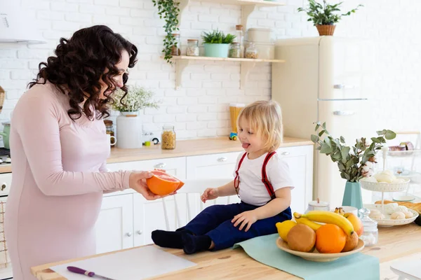 Mother feeds her son with an orange. — Stock Photo, Image