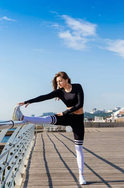 Mujer deportiva estirándose cerca del mar . — Foto de Stock