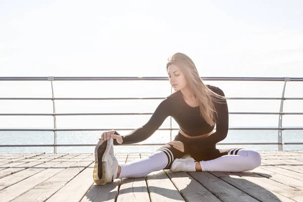 Sport woman outdoor doing stretching exercises.