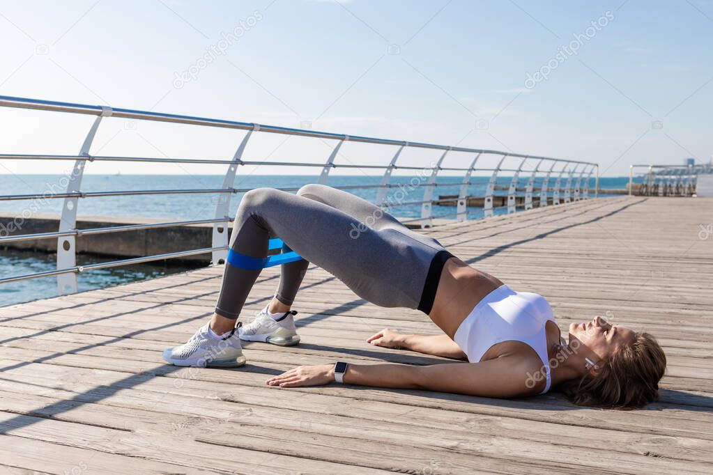 Woman doing exercises on wooden foor embankment.