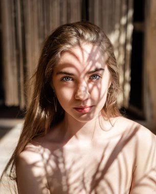 Yüzünde gölgeler olan güzel bir genç kadının portresi. Işık ve gölge. Sıradışı gölgelerle kaplı genç bir kızın ilginç bir portresi..