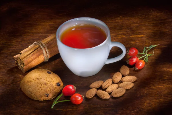 Christmas concept with a cup of hot tea, cookies and decorations on a log over wooden background, selective focus — Stock Photo, Image