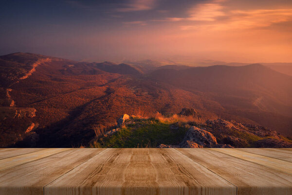Autumn beautiful background with sunset over mountains. empty wooden table in nature outdoor. Natural template landscape