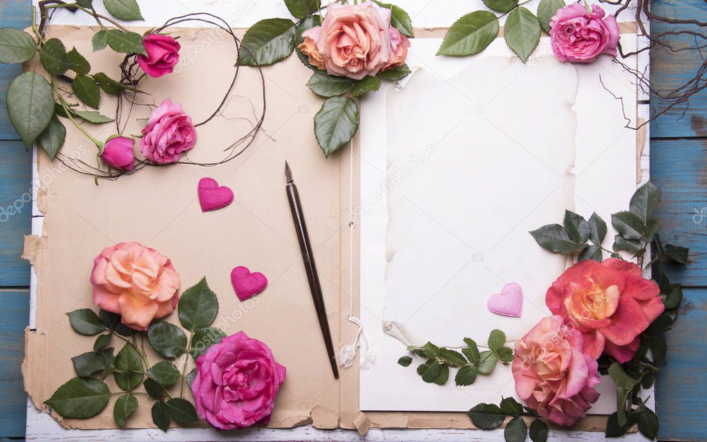 aged paper sheets with fresh rose flowers and old nib pen brush