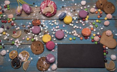 rustik ahşap masa üzerinde boş kağıt levha ile çeşitli renkli pasta 