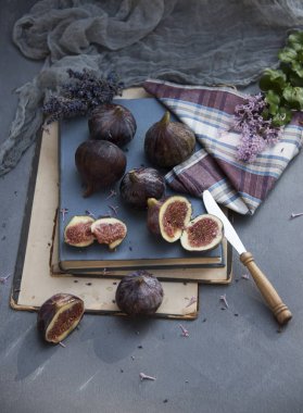 incir meyve üzerinde peçete, kitap ve eflatun çiçekler ile kompozisyon