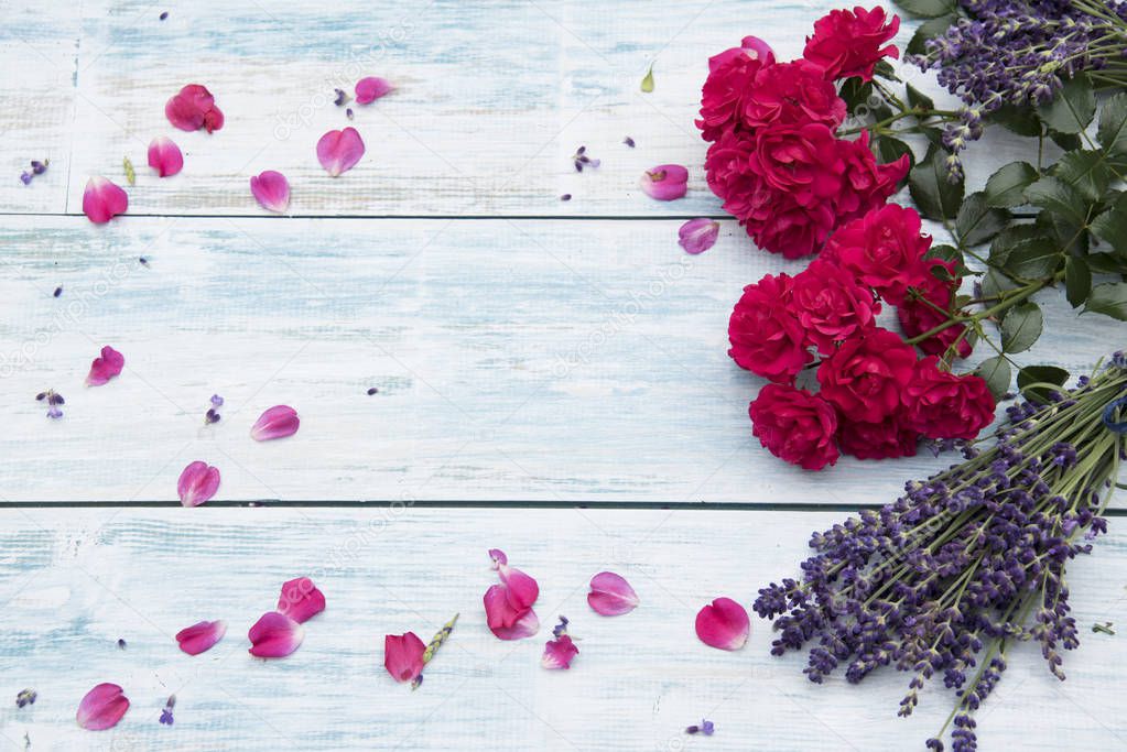 roses and bunches of lavender flowers on rustic wooden table 