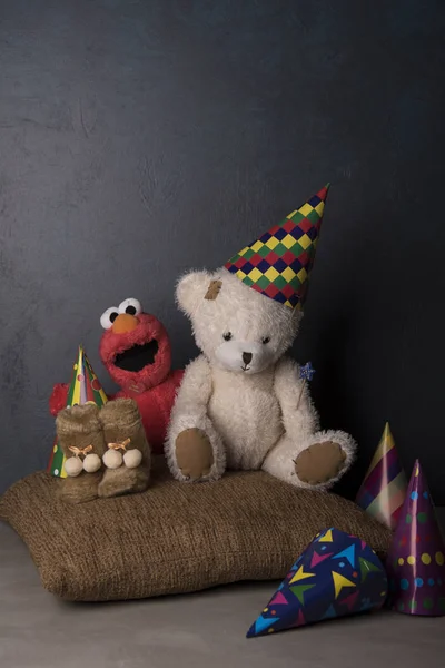 Teddy bear in Birthday hat and pink toy on brown pillow