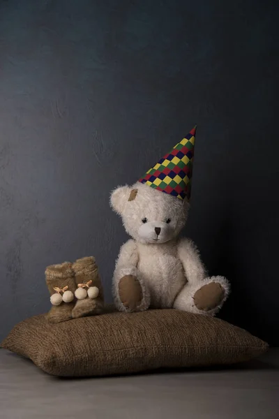 Teddy bear in Birthday hat on brown pillow