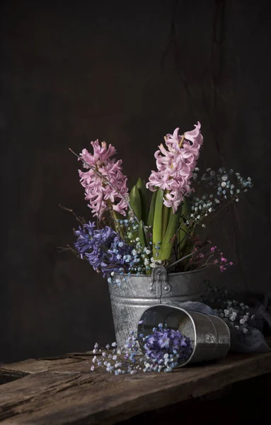 close up of hyacinth flowers in bucket on wooden table