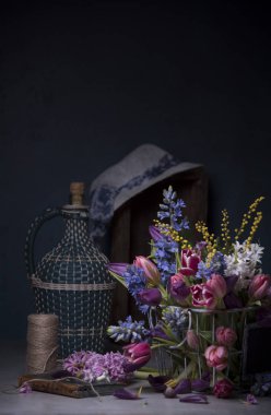 kompozisyon farklı bahar çiçek metal sepet, sürahi ve koyu arka plan üzerinde beyaz şapka  