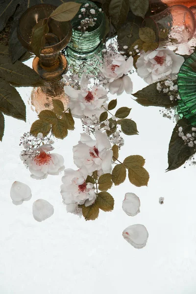 close up of glasses and flowers on mirror background