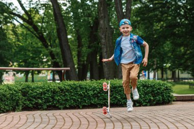Bir küçük şehir çocuğu ve bir kaykay. Genç bir adam bir parkta bir kaykay üzerinde biniyor. City Style. Şehir çocukları. Bir çocuk bir kaykay binmek öğrenir