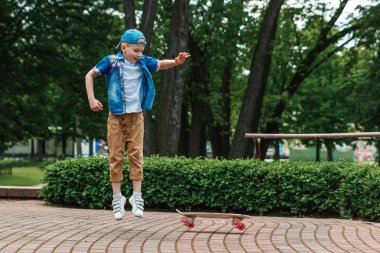 Bir küçük şehir çocuğu ve bir kaykay. Genç bir adam bir parkta bir kaykay üzerinde biniyor. City Style. Şehir çocukları. Bir çocuk bir kaykay binmek öğrenir