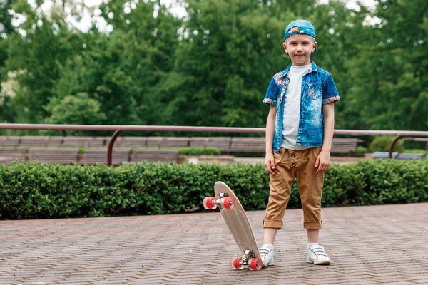 A small city boy and a skateboard. A young guy is riding in a park on a skateboard. City Style. City children. A child learns to ride a skateboard