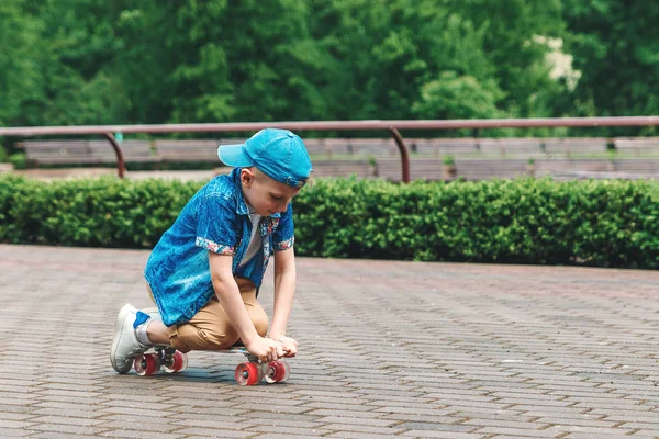 A small city boy and a skateboard. A young guy is riding in a park on a skateboard. City Style. City children. A child learns to ride a skateboard