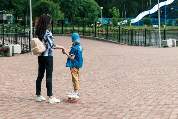 Genç güzel anne oğluyla eğleniyor ve açık havada buz pateni küçük neşeli. Annesi dışında kaykay ile dinlenme birlikte ile çok güzel bir çocuk. Mutlu bir aile